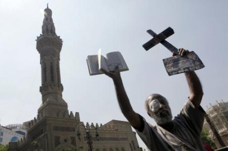 An Egyptian protester holds a cross and a copy of Islam's holy book, the Quran, during a protest in Tahrir Square to condemn sectarian clashes in Egypt, 2013. Amr Nabil /Press Association. All rights reserved. 